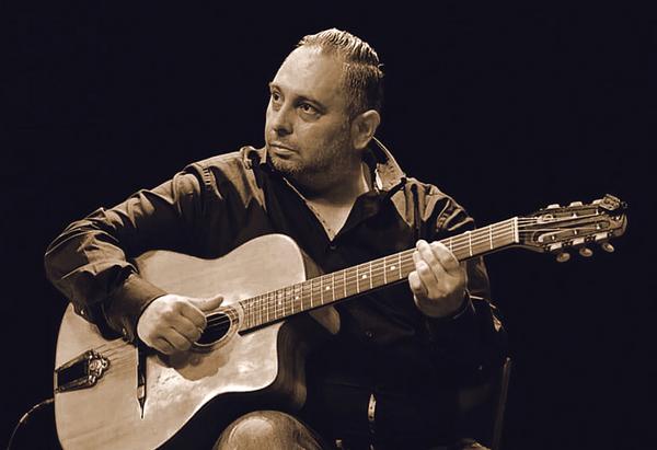 Zwischen den Noten des Lebens Musiker mit Gitarre vor schwarzem Hintergrund. Textabbildung: „Zwischen den Noten des Lebens“