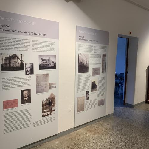 Ausstellung zur 'Aktion 3' in Herford – Dokumentation der Enteignung und Wiedergutmachung jüdischen Eigentums Ausstellungstafeln zur 'Aktion 3' in Herford mit Informationen über die Enteignung jüdischen Eigentums von 1942 bis 1945 und die Wiedergutmachung nach 1945, ausgestellt in einem Museumsgang.